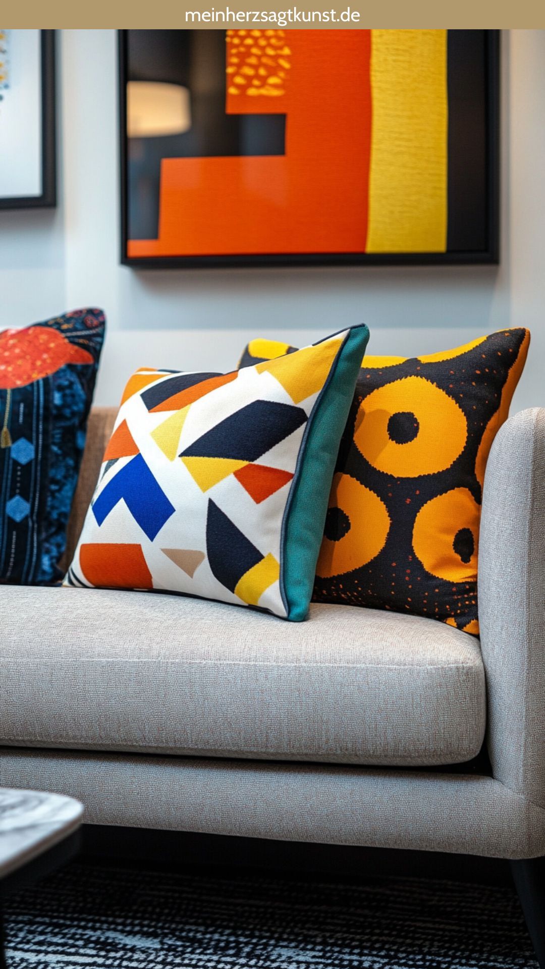 Graues Sofa mit Kissen in geometrischen Mustern und kräftigen Farben