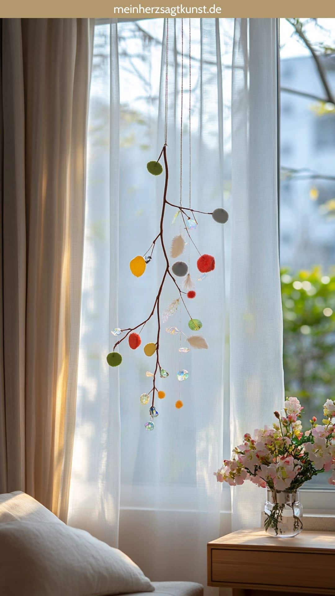 Frühlingshaftes Mobile mit Zweigen und Anhängern am Fenster
