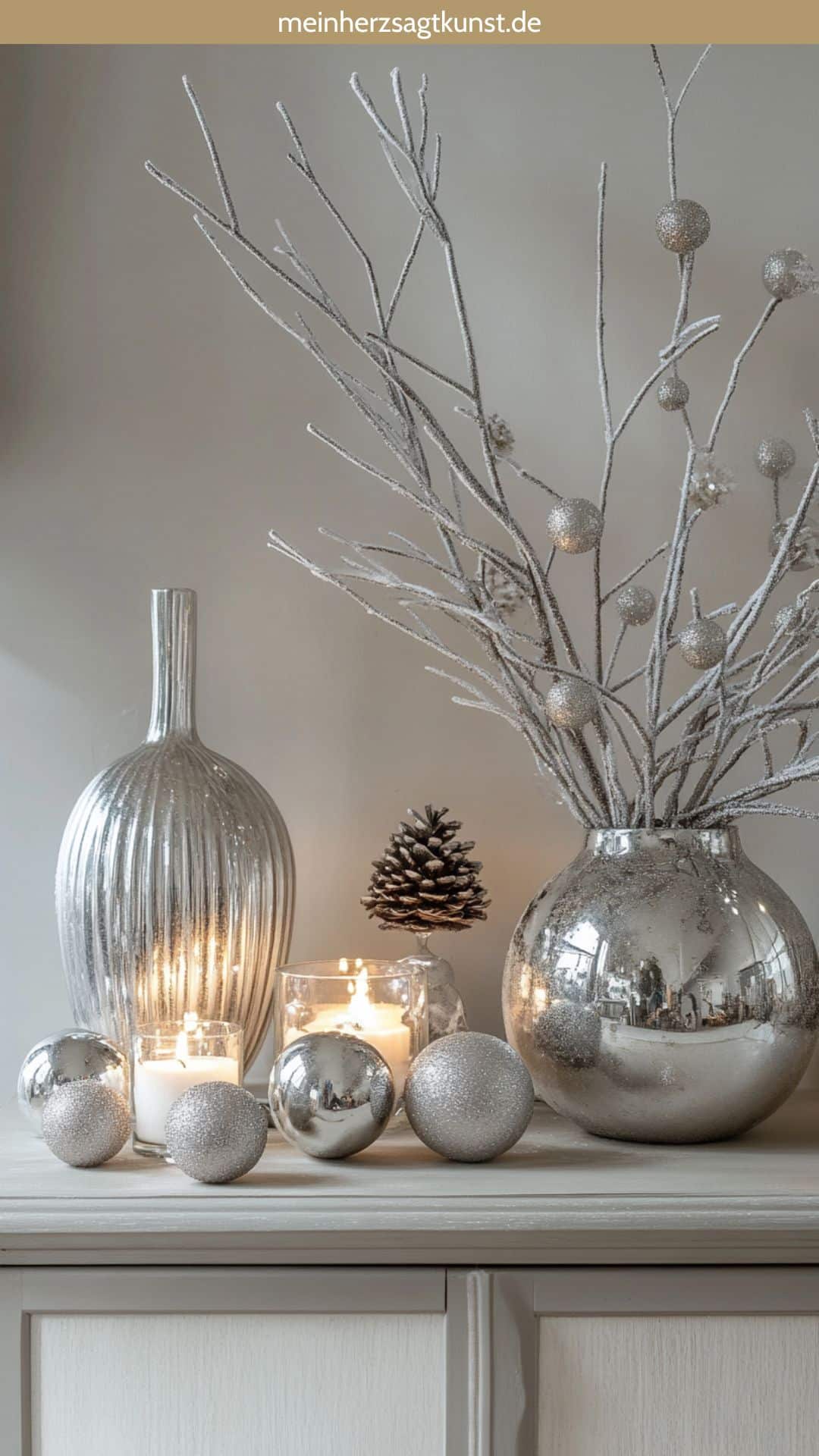 Glasvasen und Silberaccessoires auf einem winterlich dekorierten Sideboard.